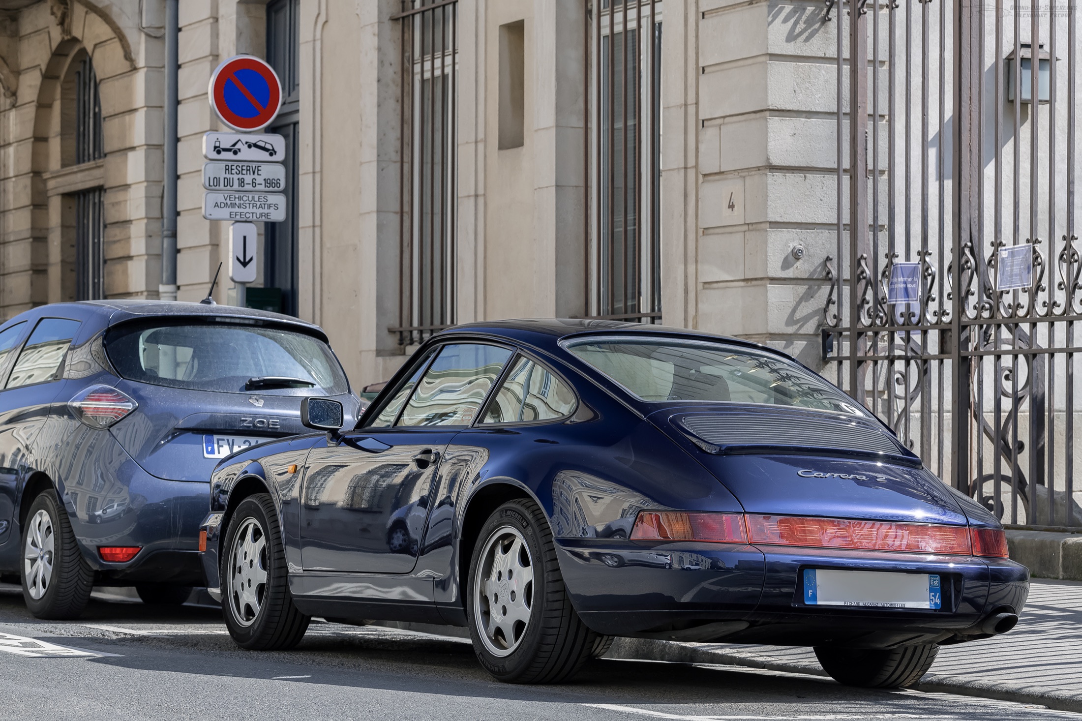Dunkelblauer Porsche 911 Carrera 2 der Baureihe 964 aus hinterer Seitenansicht